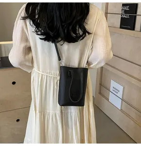 Rear view of a textured black mini crossbody bag worn by a model in a minimal setting