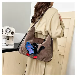 Détail du cabas vintage en daim marron avec broderie chat porté par un mannequin
