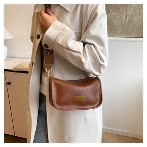 Detail of a brown leather crossbody bag with a stylish leopard print wide strap