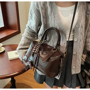 Detail of dark brown glossy leather boston bag with chocolate and puppy charms