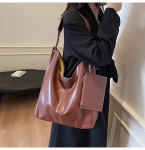 Detailed side view of brown leather hobo bag with contrast stitching and small pouch