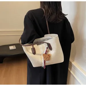 Detailed back view of a large cream tote bag with brown straps worn by a model