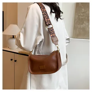 Detail of vintage brown leather bag with white stitching and leopard print wide strap