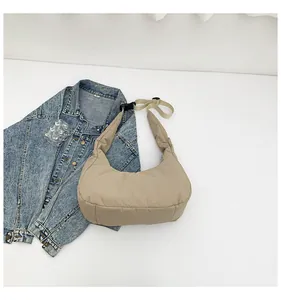 Detail of padded beige nylon crescent bag with adjustable wide strap and buckle