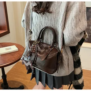 Detail of dark brown leather Boston bag with chocolate and puppy charms on model