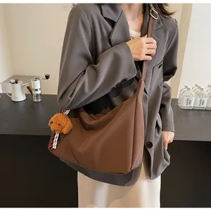 Detail einer braunen Hobo-Tasche mit süßem Plüsch-Hundeanhänger und goldener Schnalle