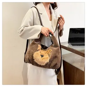 Gros plan sur un sac hobo en velours marron avec écusson Schnauzer brodé