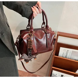 Detail view of burgundy vintage boston bag with glossy leather and puppy charm
