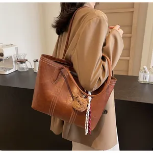Brown leather tote bag detail with white contrast stitching and cute bear charm decor