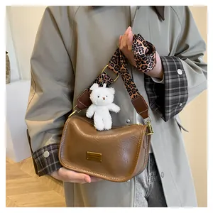 Detail of a brown retro Boston bag featuring a leopard print strap and bear charm