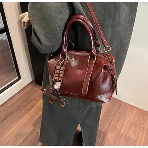 Close-up of wine red glossy leather pillow bag with charms and gold-tone hardware