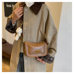 Brown Boston bag with a leopard strap and plush bear charm shown on a stylish trench coat