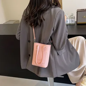 Pink mini crossbody bag for women in textured leather shown with casual street outfit