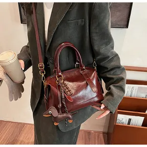 Close-up of retro dark red-brown Boston bag with cute dog pendant and chocolate charm