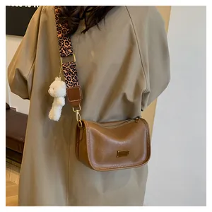 Detail of vintage brown crossbody bag with leopard print strap and plush bear charm