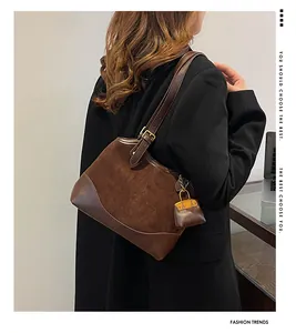 Detail of dark brown bucket bag with mixed textures and decorative mini charm