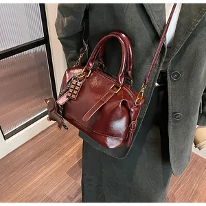 Detail of burgundy glossy handbag worn with green velvet coat and cute puppy charm
