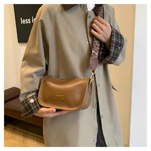 Detail of vintage brown crossbody bag with leopard print strap and golden metal plaque