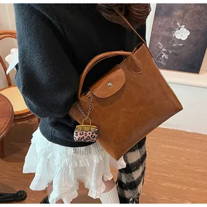 Detail van een bruine handtas met een trendy mini-bedeltje in luipaardprint