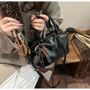 Detail of black glossy Boston bag with gold zipper and playful chocolate dolphin charms