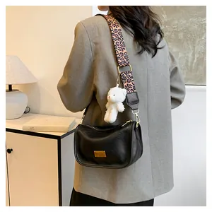 Detail of black crossbody bag with pink leopard strap and plush bear charm