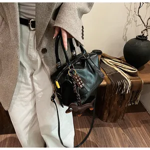 Detail of vintage black leather Boston bag featuring dog charm and chocolate pendant