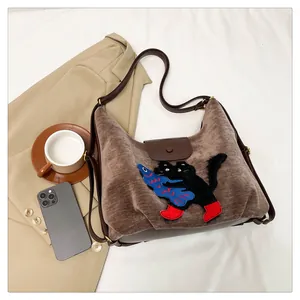 Détail du sac cabas en velours côtelé marron avec broderie chat et sangle en cuir chic