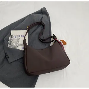 Detail der dunkelbraunen Hobo-Tasche mit kariertem Schal und Plüsch-Anhänger Dekor