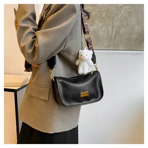 Detail of black Boston bag with leopard print strap and white bear charm