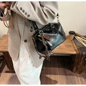 Detail of black glossy Boston bag with chocolate charms and gold hardware in street style