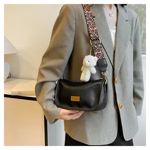 Detail of black PU leather Boston bag with leopard print strap and plush bear charm