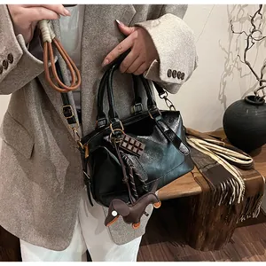 Detail of a black leather pillow bag with a brown dachshund charm and gold hardware