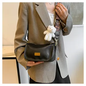 Close-up of black leather crossbody bag with leopard print strap and plush bear charm