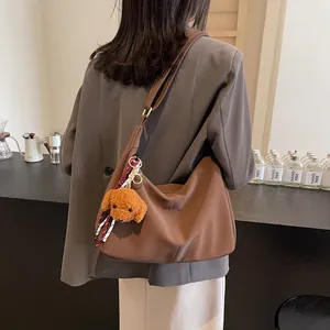Braune Hobo-Schultertasche aus mattem Kunstleder mit einem süßen Teddybär-Plüschanhänger