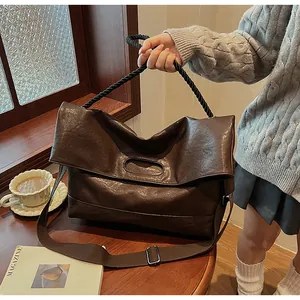 Détail d'un sac cabas en cuir marron foncé avec anse corde et bandoulière réglable