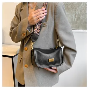 Detail of black pebbled leather bag with leopard print strap and gold metal logo