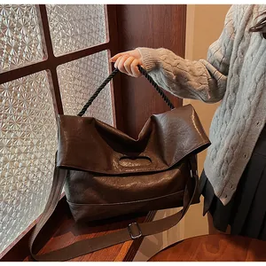 Détail du grand sac cabas marron foncé montrant le cuir vintage et les anses torsadées