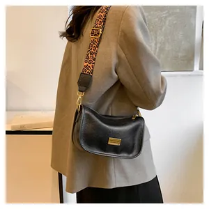 Detail of black Boston bag with gold metal plate and leopard print fabric strap