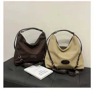Detail view of large tote bags with pleated nylon, leather trim, and adjustable metal buckles
