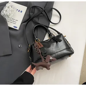 Detail of vintage black faux leather pillow bag with brown dachshund charm and gold hardware