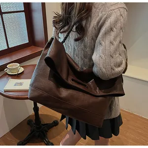 Détail d'un grand cabas en cuir marron foncé avec une bandoulière unique en corde torsadée