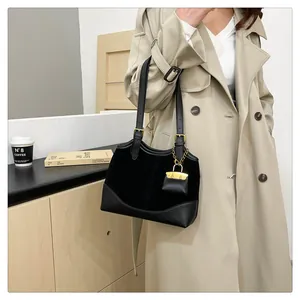 Detail of black tote bag featuring wave-cut edge and delicate gold chain ornament