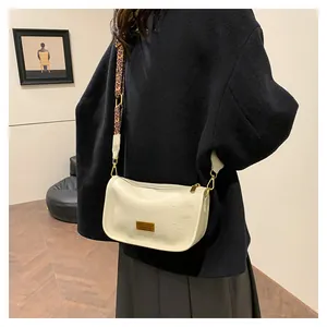 Detail of cream crossbody bag with leopard print wide strap and gold metal logo plaque
