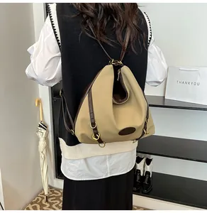 Detail of khaki and brown canvas backpack showing pleats and buckle on a model