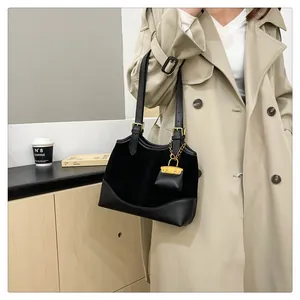 Detail of black bucket bag featuring textured leather panels and a mini charm accessory