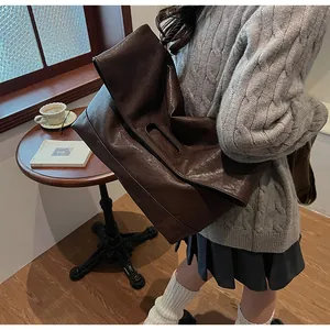 Vue de dessus d'un grand sac cabas marron en cuir souple avec anses évidées dans un café