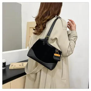 Detail view of the black mixed-material bucket bag with orange mini charm accessory