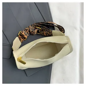 Top view of cream Boston bag featuring leopard print strap on grey blazer background