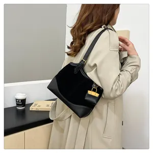 Detail of black suede shoulder bag with decorative yellow mini pouch charm worn by a model