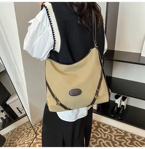 Detail of khaki hobo bag with brown leather trim and metallic buckle on shoulder